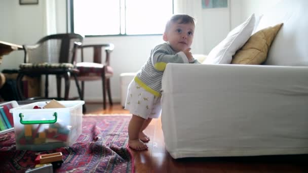 Αξιολάτρευτο Μωρό Που Μαθαίνει Στέκεται Ακουμπώντας Στον Καναπέ Χαριτωμένο Νήπιο — Αρχείο Βίντεο