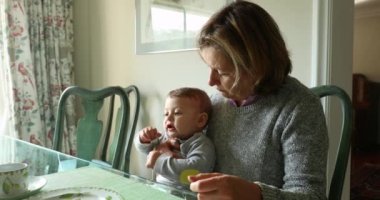 Candid authentic grandmother with grandson at table in casual way