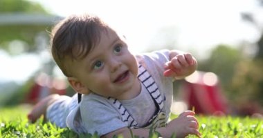 Crying baby toddler laid on grass outside in nature