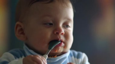 Cute baby face portrait closeup. Infant toddler teething biting spoon
