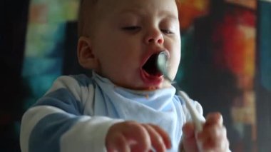 Cute baby playing with spoon. Playful toddler holding spoon during lunch