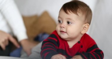 Cute baby toddler on sofa learning and discovering the world during first months of life