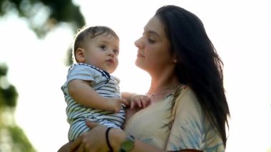 Mother caring, cuddling, and holding baby child infant son