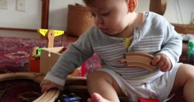 Baby learning to play with toys at home with traditional wooden toys pieces