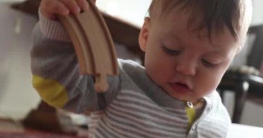 Baby toddler playing with toys at home, infant boy holding wooden piece road toy