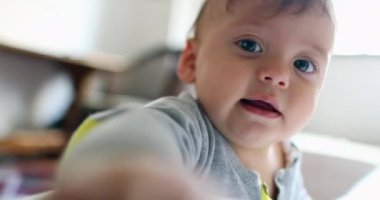 Cute baby toddler touching camera lens, closeup of infant face upset looking inside camera