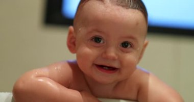 Authentic cute baby toddler holding into bathtub clapping hands