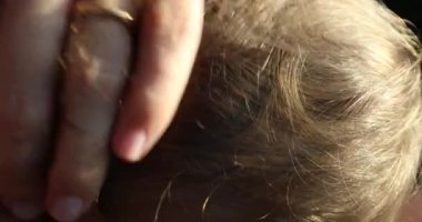 Mother caressing baby blond hair while breast-feeding