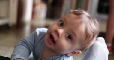 Cute baby toddler grabbing father jeans wanting to touch camera lens. Infant face smiling