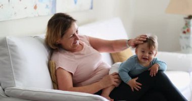 Authentic grandmother with grandson in living room sofa