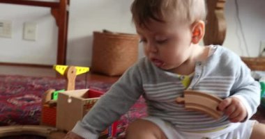 Infant baby playing with traditional wooden toys at home