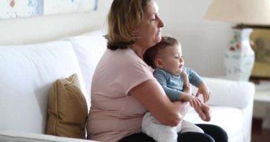Casual grand-mother with grandson in living room sofa at home, candid and authentic