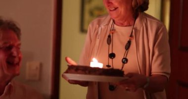 Yaşlı çift doğum gününü pasta ve mumlarla kutluyor. Eşim kocama pasta getiriyor, sıradan ve otantik.