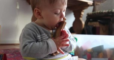 Baby playing with toys at home. Toddler infant holding wooden toy roads pieces