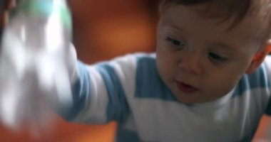 Adorable baby infant playing with plastic water bottle, toddler putting object in mouth teething