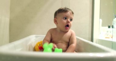 Happy baby inside bathtub splashing water with joy