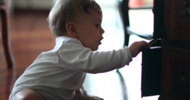 Baby toddler opening antique furniture cabinets and drawers