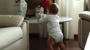 Cute baby learning to stand by holding into table