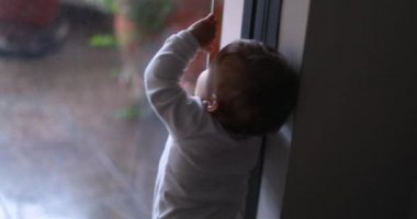 Baby infant wanting to open window, looking out, desire to go outside