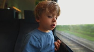 Little boy leaning on train window traveling on railroad