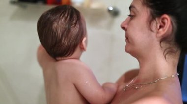 Mother holding baby infant inside bath shower