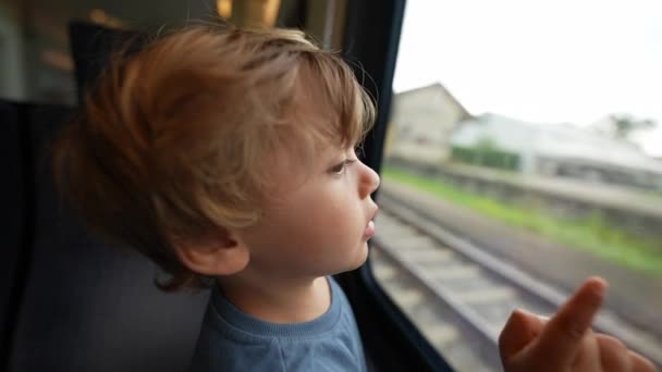 Child Travels Train Leaning Window Pointing Landscape Passing — Video