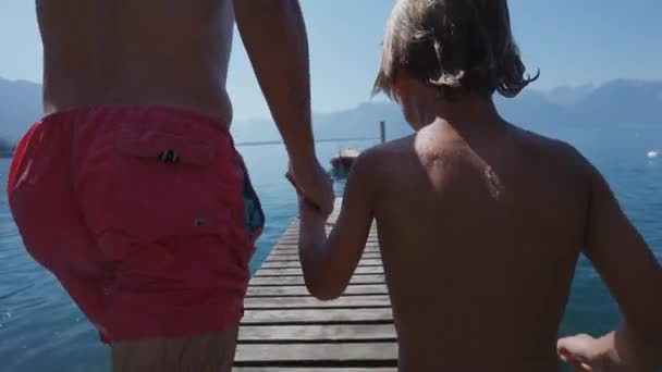 Πατέρας Και Παιδί Τρέχουν Στην Προβλήτα Και Πηδούν Στο Νερό — Αρχείο Βίντεο