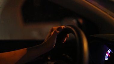 Hands holding steering wheel driving at night in slow-motion