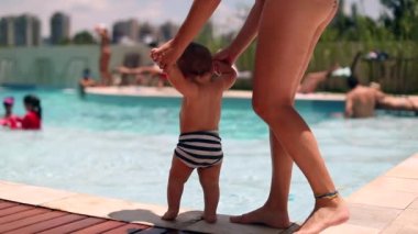 Mother with baby toddler at the swimming pool during summer vacations
