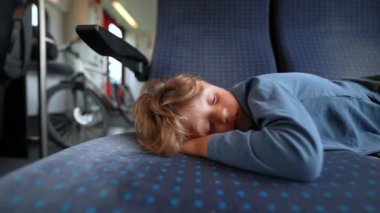 Young boy sleeping on train child lying down on passenger seat asleep