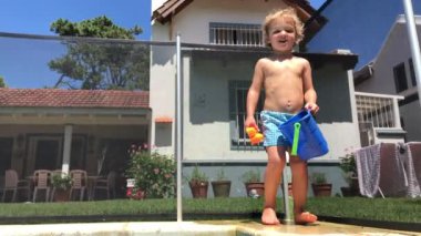 Toddler baby boy looking at camera in swimming pool setting happy