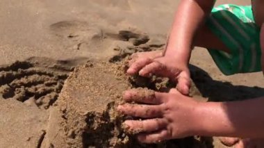 Baby hands playing with sand at the beach