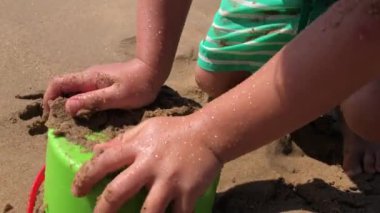 Baby toddler playing with sand and bucket at the beach