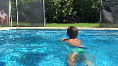 Çocuk havuzda yüzüyor.