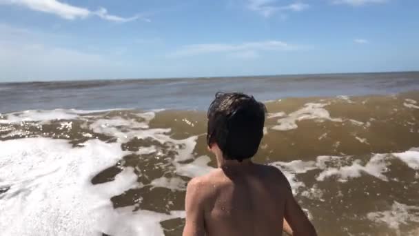 幸せな子供がビーチで遊んで波がクラッシュ — ストック動画