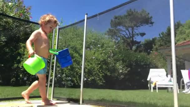 Toddler Boy Walking Poolside Holding Bucket — Vídeos de Stock