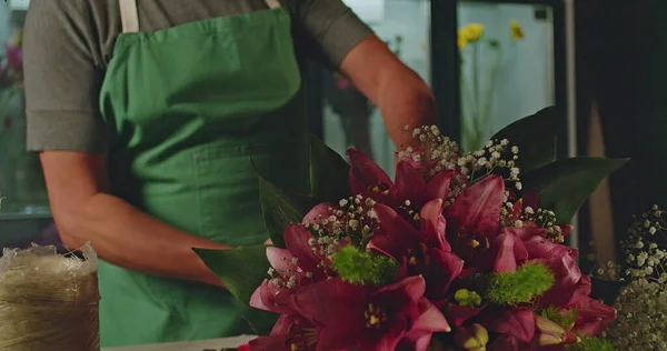 A small business employee of flower shop creating a bouquet of flowers arraignment. An Asian American entrepreneur creating artisan bouquet for client