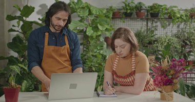 Female employee working at local small business store taking online orders using tablet modern device. Young woman staff managing inventory
