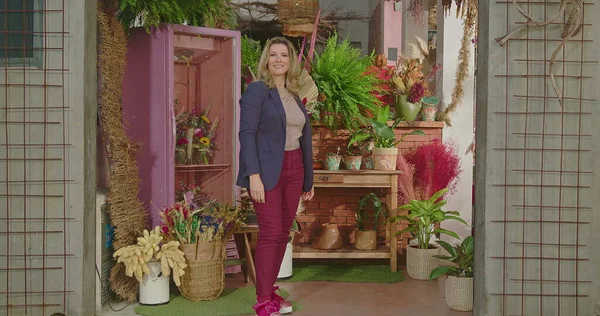 Businesswoman owner of local flower store standing in front of business. Portrait of a female entrepreneur smiling at camera