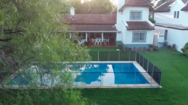 Exterior of home with garden lawn and swimming pool. House captured with drone