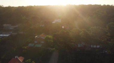 Flying over suburb homes during sunset golden hour time