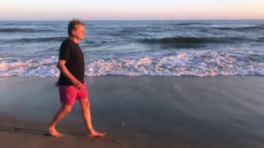 Senior man walking at the beach during sunset