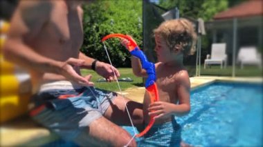 Çocuk ve baba birlikte yüzme havuzunda.