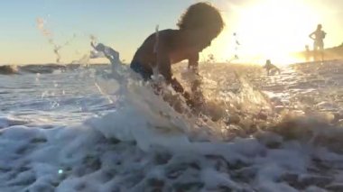 Yürüyen çocuk plaj dalgalarıyla oynuyor.