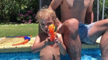 Çocuk oyuncakla kameraya su atıyor.