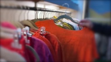 Consumer choosing clothing at store, person picking pulling clothes from hangers