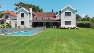 Exterior of house with lawn and swimming pool in bright beautiful day