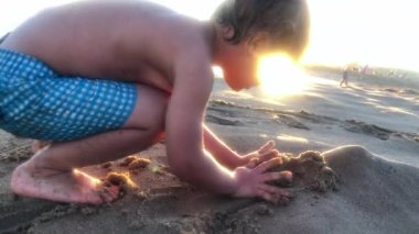 Toddler baby boy playing with sand beach