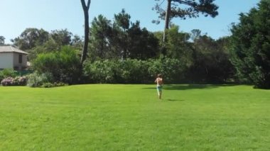 Child running in home garden during bright sunny day. Boy running outdoors