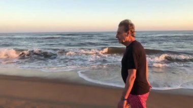 Retired senior man walking at the beach during sunset